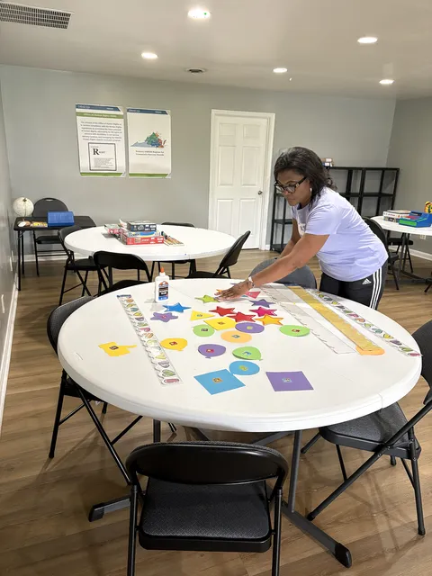 A Gregory & Friends staff member setting up a colorful shape-and-star learning activity on a round table