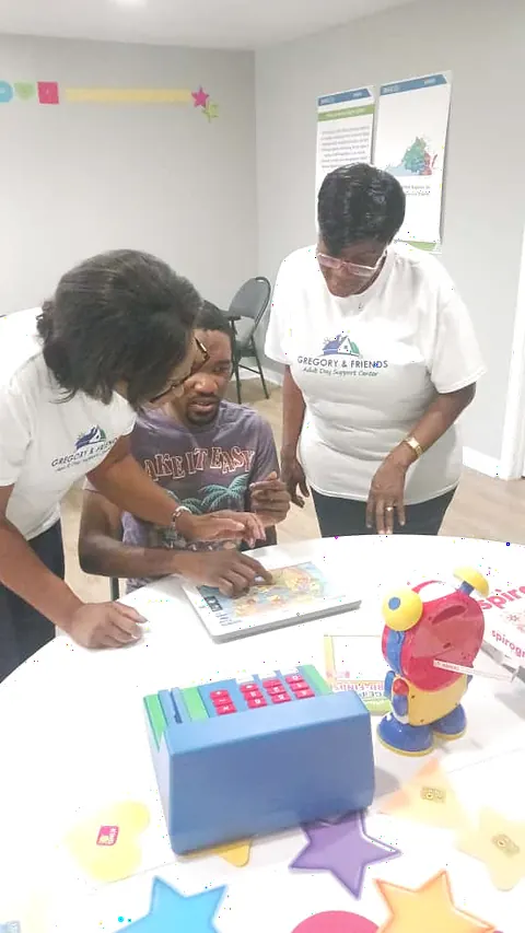 Staff and a participant exploring a USA map puzzle together at Gregory & Friends
