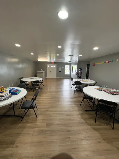 The bright, spacious main activity room at Gregory & Friends with round tables set up for the day