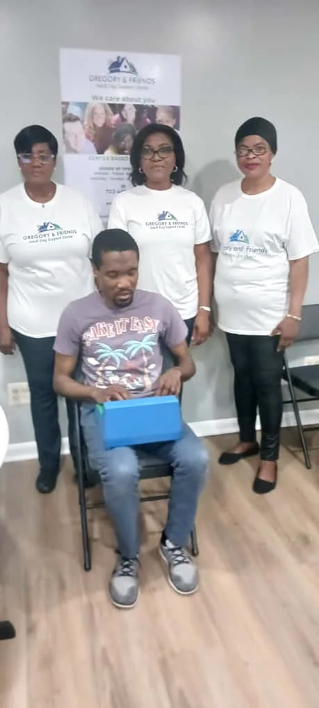 Gregory seated with three Gregory & Friends staff members in branded shirts standing behind him at the center