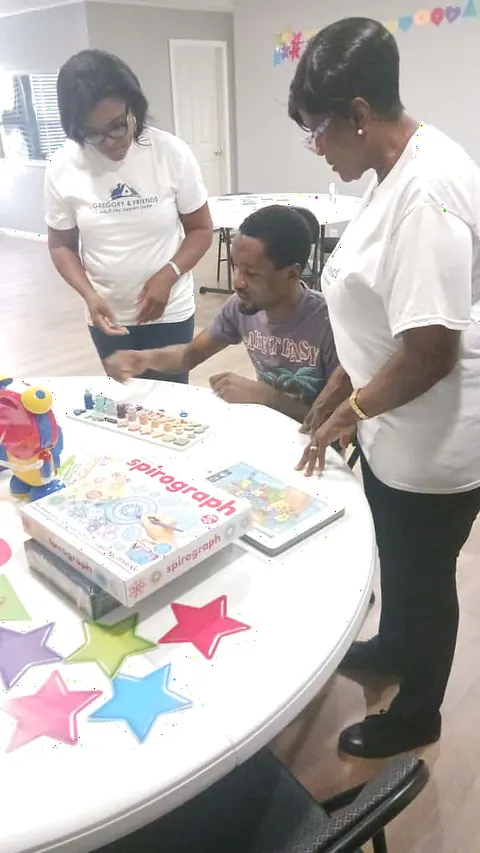 Staff and a participant working together on a colorful tile-sorting activity at Gregory & Friends