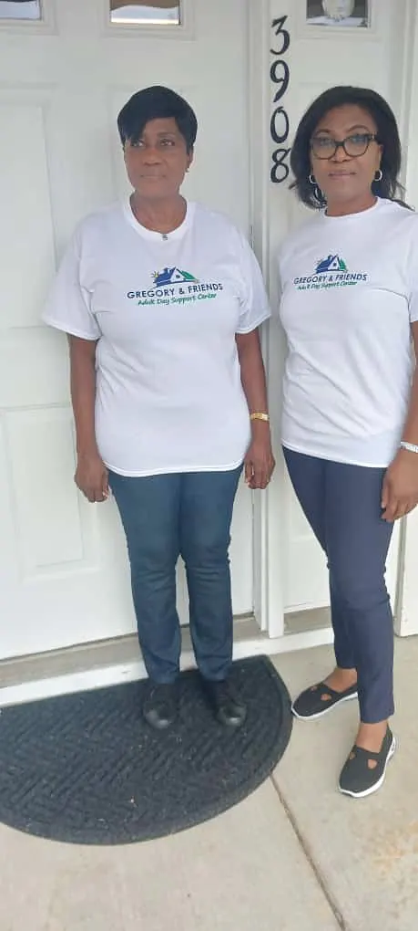Two Gregory & Friends caregivers in branded shirts at the entrance of the center